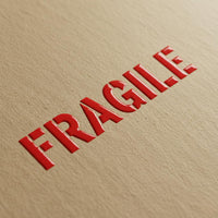 Vibrant red 3D embossed UV sticker reading Fragile applied to brown kraft paper texture