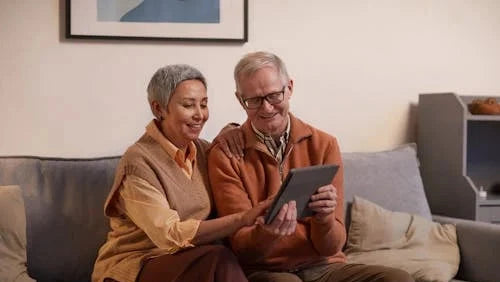 Elderly couple looking at photos on a tablet, illustrating the need for an easy-to-use Picrora digital frame for grandparents.