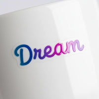 Blue and purple gradient UV transfer decal reading Dream applied to a white ceramic mug surface.